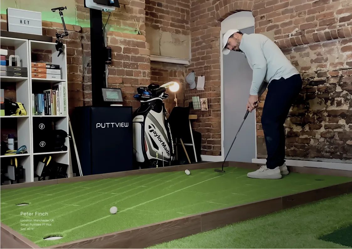 Golfista preparando un putt sobre un green elevado dentro de un estudio con muros de ladrillo.